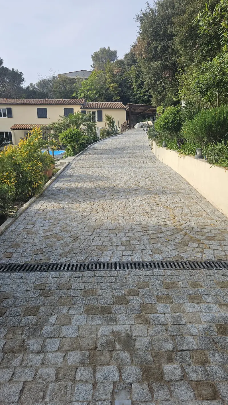 Allée en pavés de granit posés en éventail montant vers une villa