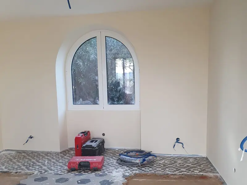 Pose de carreaux de ciment sous une fenêtre cintrée