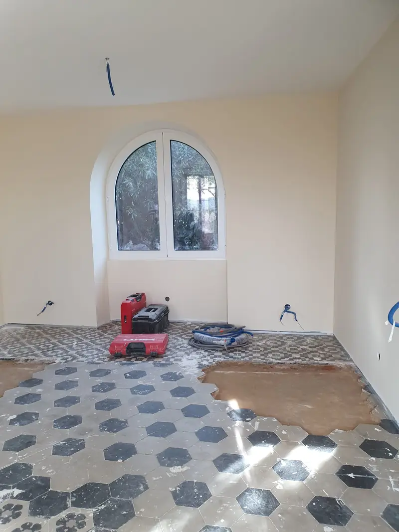 Pose de carreaux de ciment sous une fenêtre cintrée