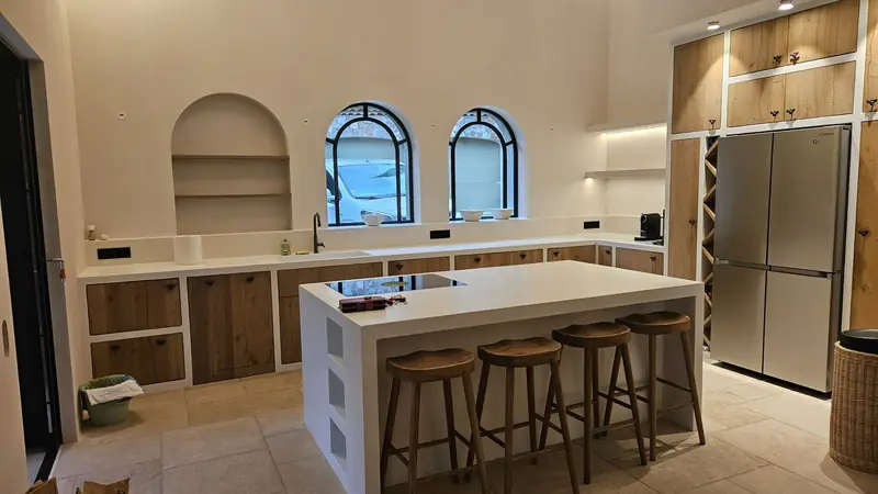 Cuisine terminée avec îlot central en béton ciré et tabourets