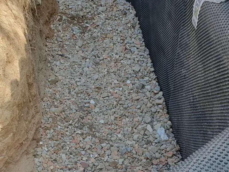 Membrane à excroissances et lit de granulat drainant en pied de mur enterré