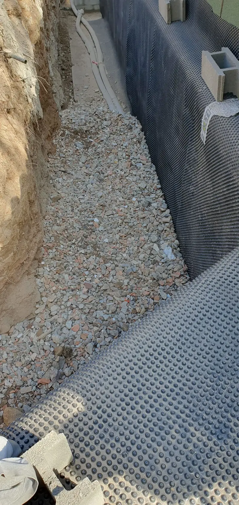 Membrane à excroissances et lit de granulat en pied de mur enterré