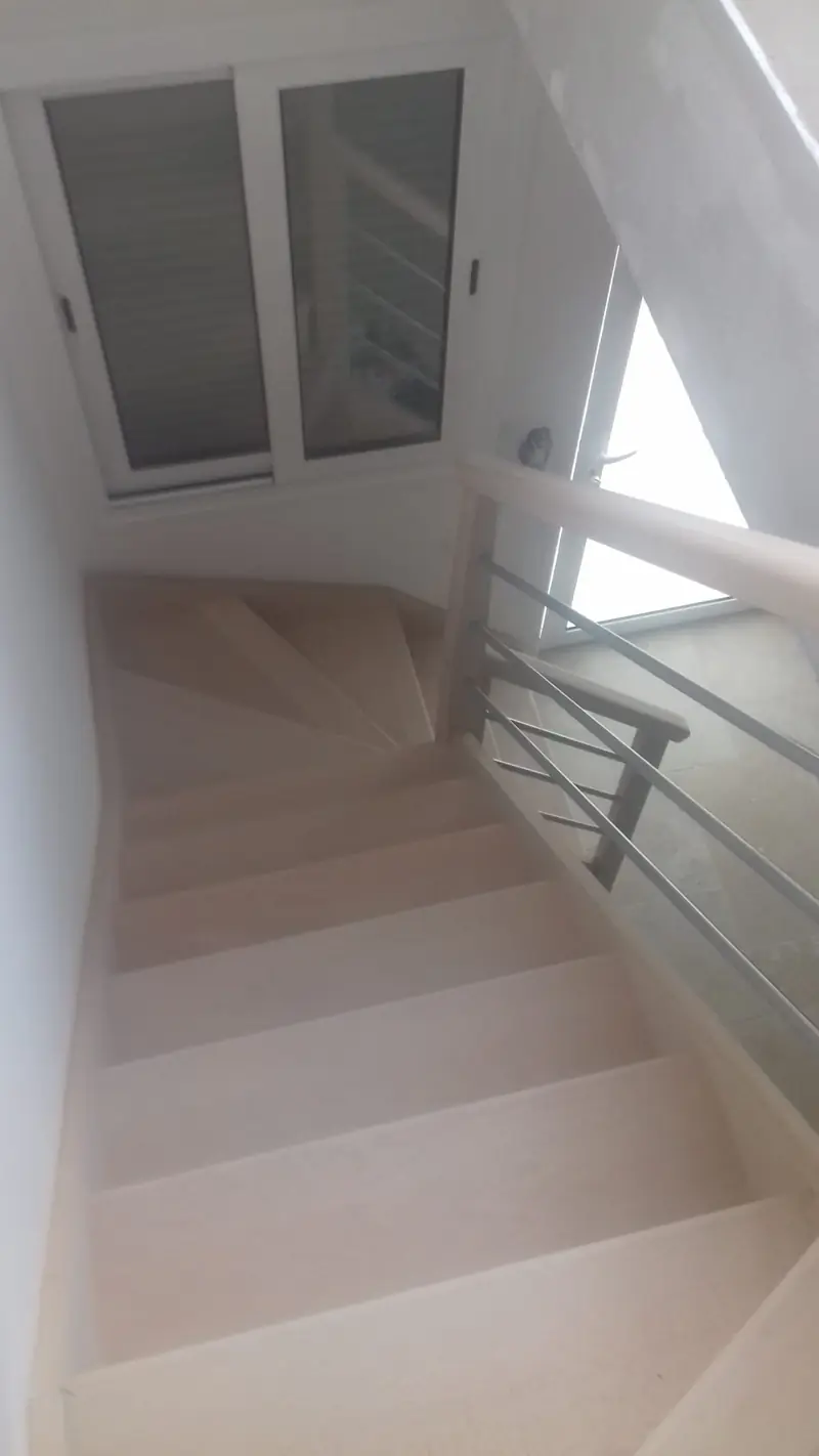 Escalier intérieur tournant en béton ciré blanc avec garde-corps