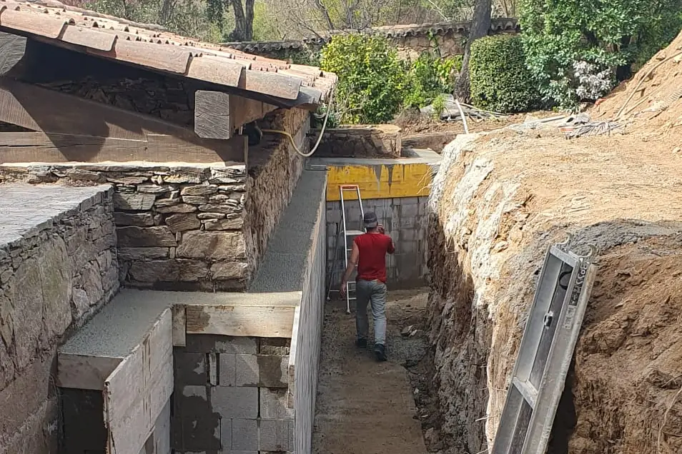 Mur de soutènement en blocs à bancher construit le long d’une tranchée sur un terrain en pente