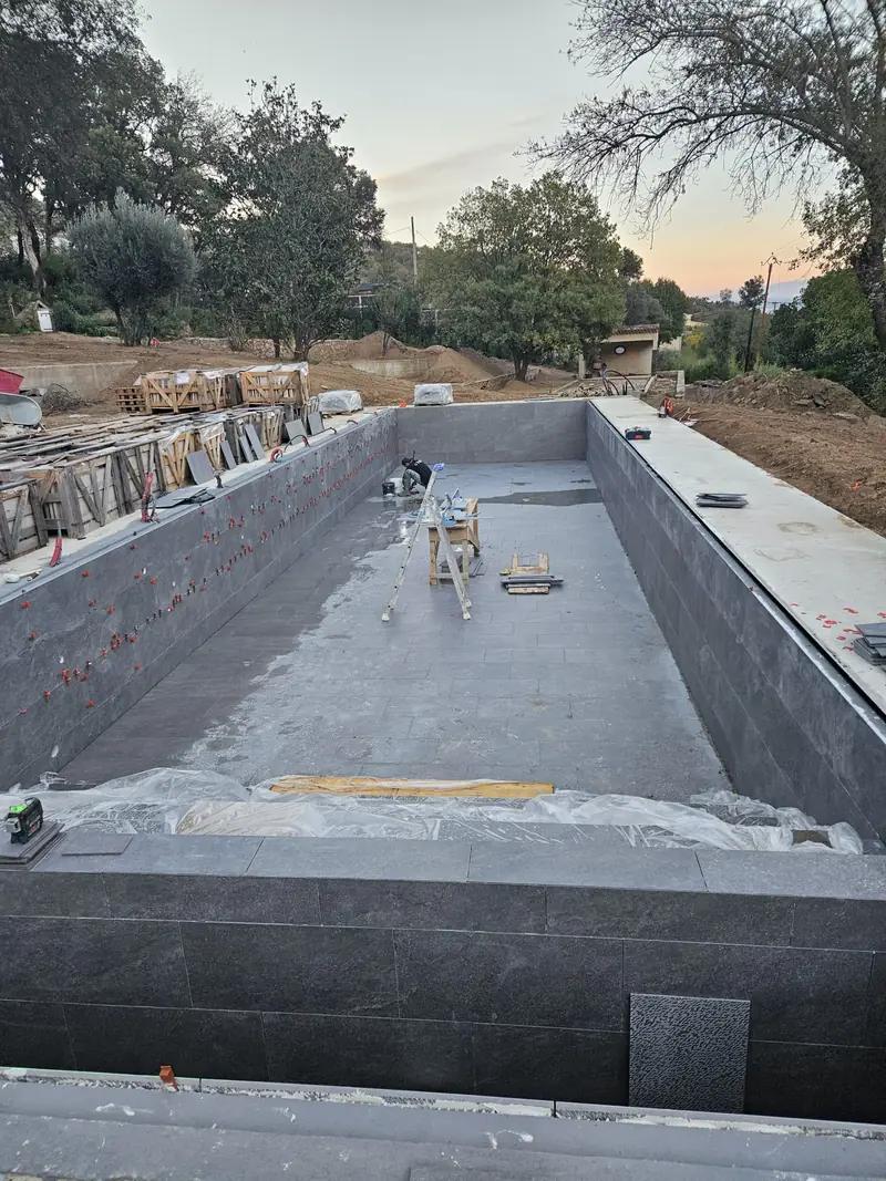 Piscine carrelée en pierre grise avec escalier immergé sur toute la largeur