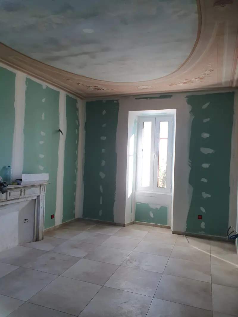 Cloisons en plaques de plâtre bandées sous un plafond à moulures conservé