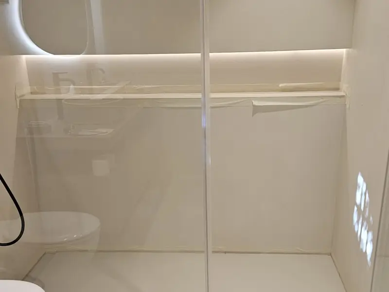 Salle d’eau en béton ciré clair avec miroir rond rétroéclairé