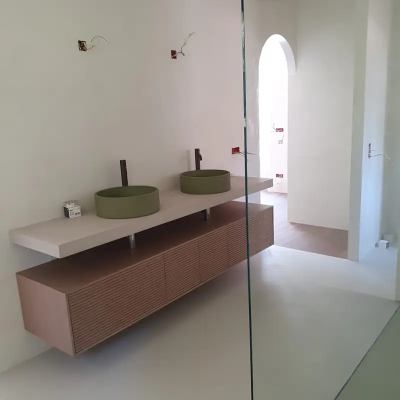 Salle de bain rénovée avec double vasque verte sur plan suspendu et meuble en bois cannelé