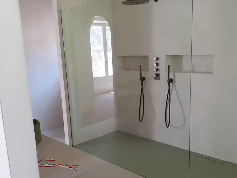 Douche à l’italienne en béton ciré vert d’eau avec niche et robinetterie noire
