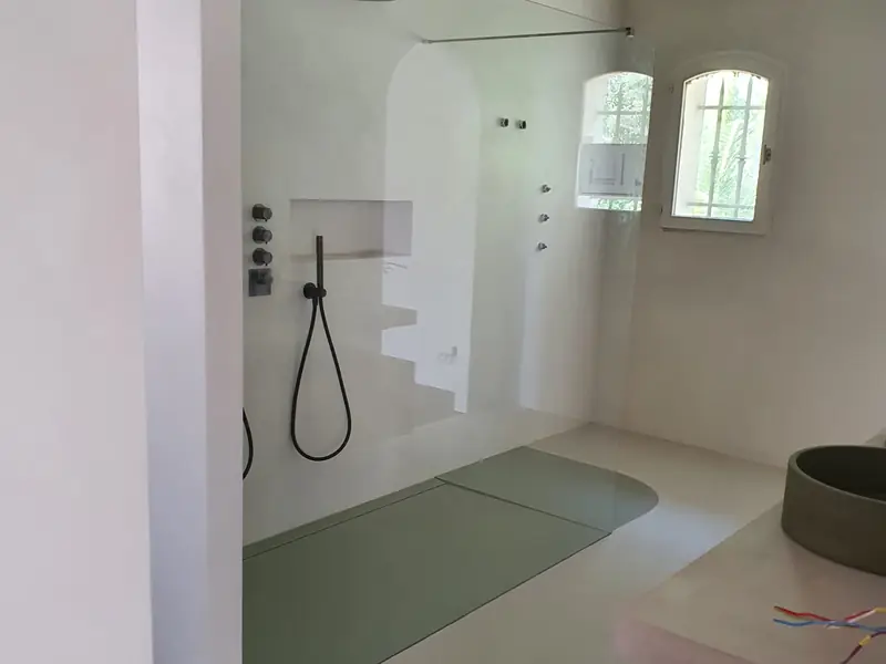 Douche à l’italienne en béton ciré ouverte sur la chambre, avec fenêtre en arche