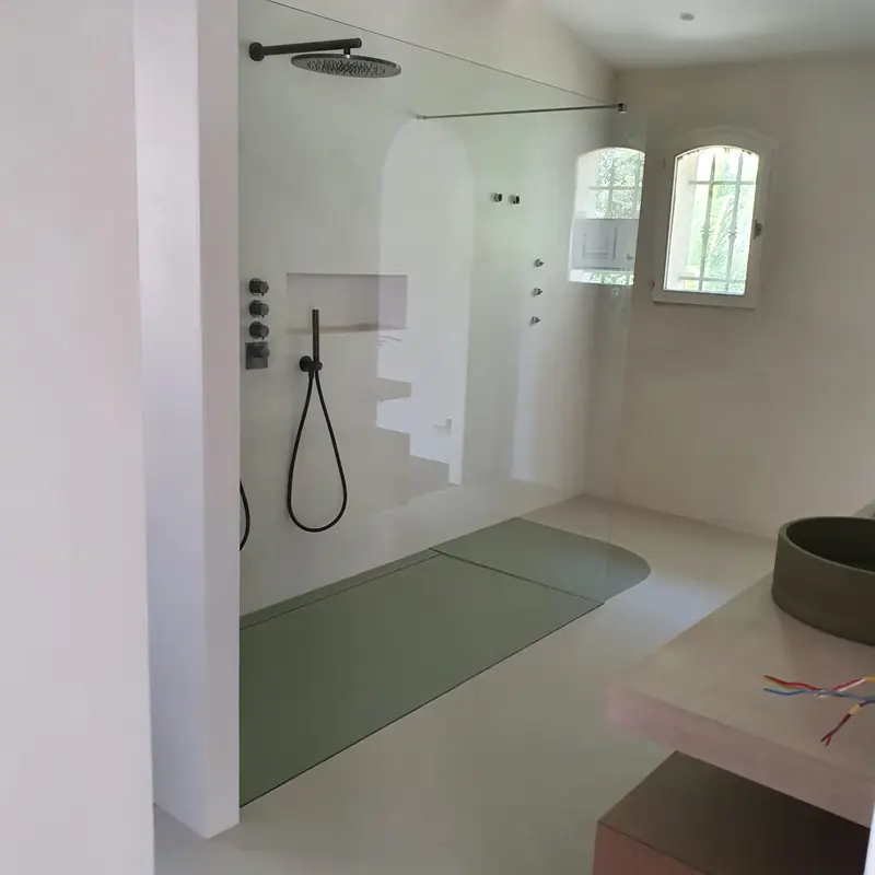 Douche à l’italienne en béton ciré ouverte sur la chambre, avec fenêtre en arche