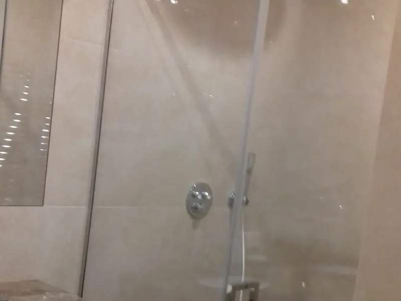 Douche carrelée beige avec paroi vitrée et mitigeur encastré