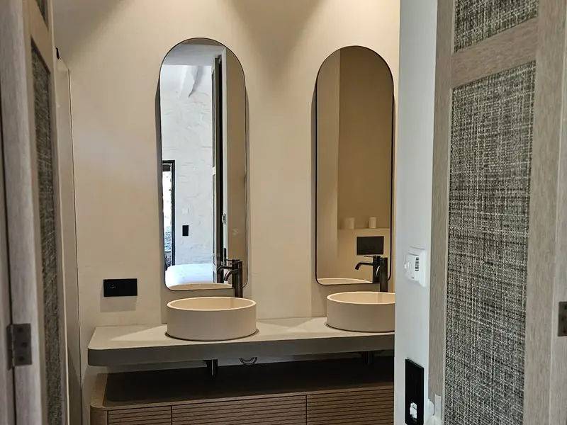 Salle de bain avec double vasque, miroirs en arche et meuble en bois cannelé