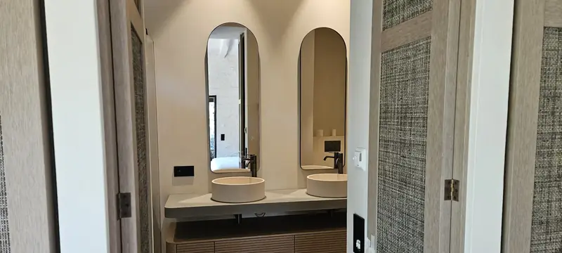 Salle de bain avec double vasque, miroirs en arche et meuble en bois cannelé