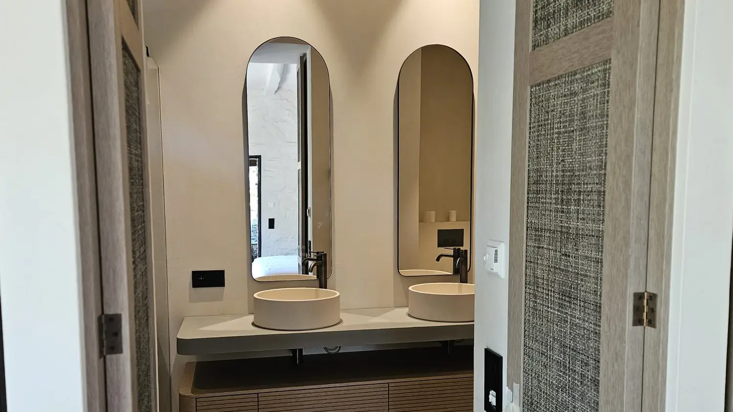 Salle de bain livrée par SP BAT : double vasque, miroirs en arche et meuble en bois cannelé