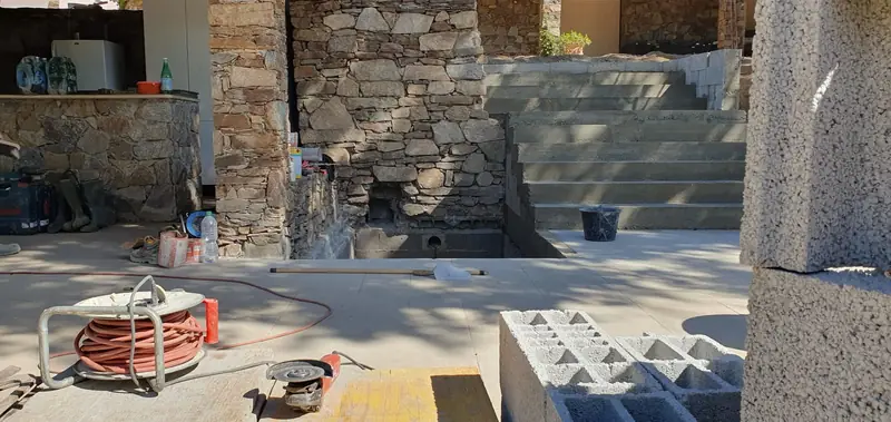 Terrasse maçonnée et emmarchement en pierre devant une cuisine d’été