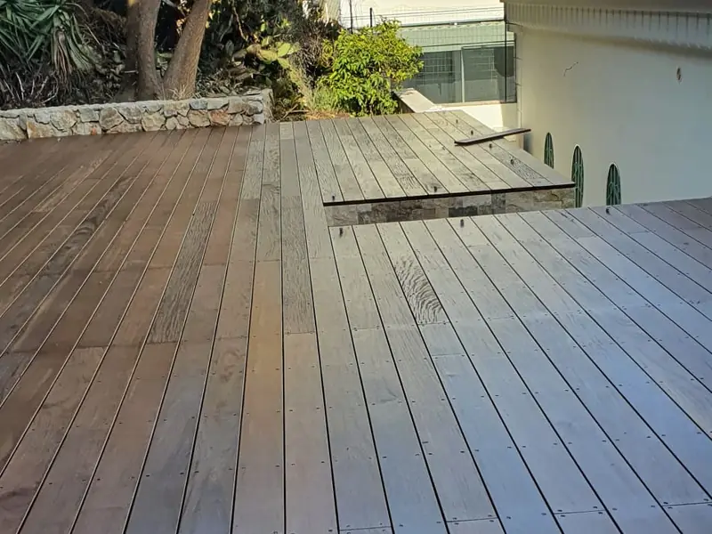 Terrasse en bois exotique terminée devant une villa à arcades