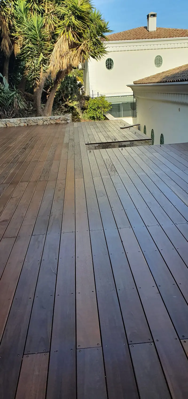 Terrasse en bois exotique terminée devant une villa à arcades