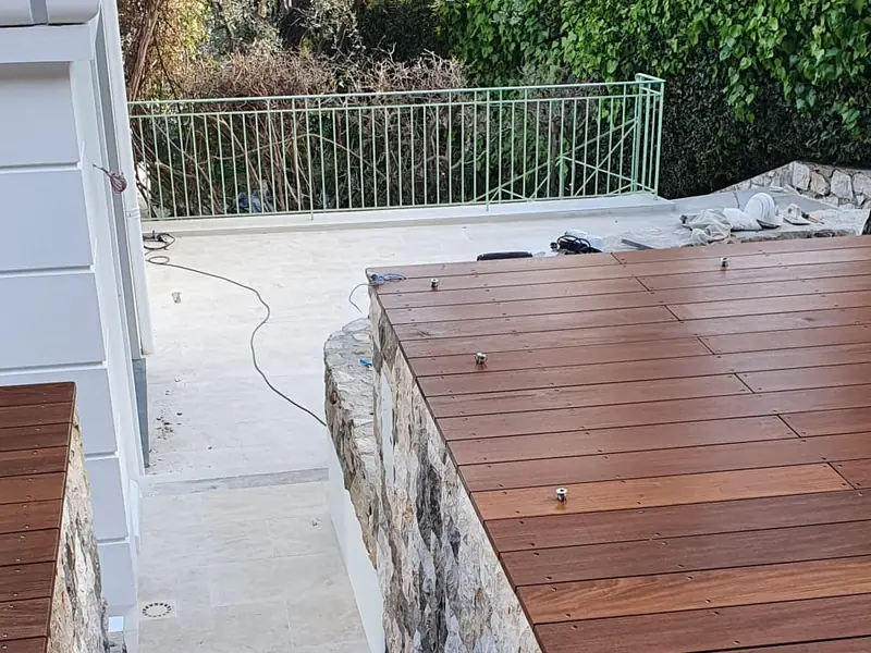 Terrasse bois en encorbellement sur un mur en pierre avec escalier en travertin