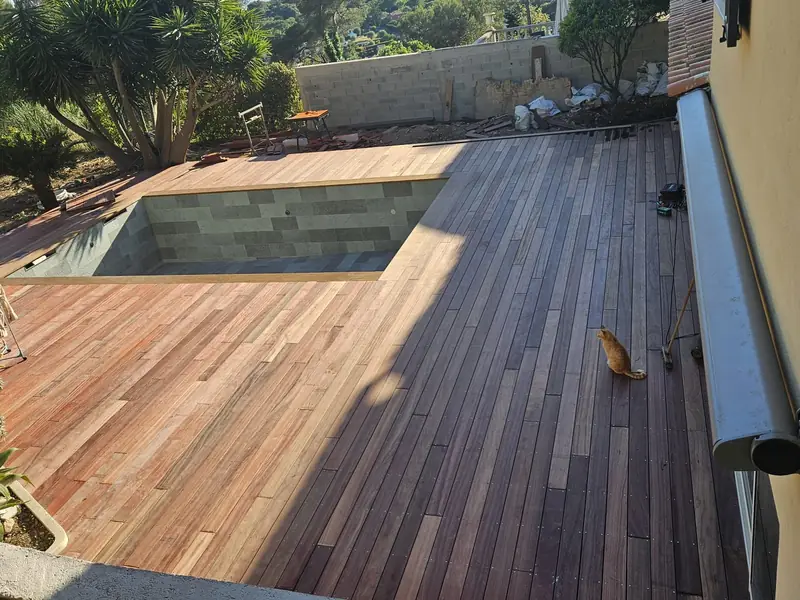 Terrasse en bois exotique terminée autour d’un bassin carrelé