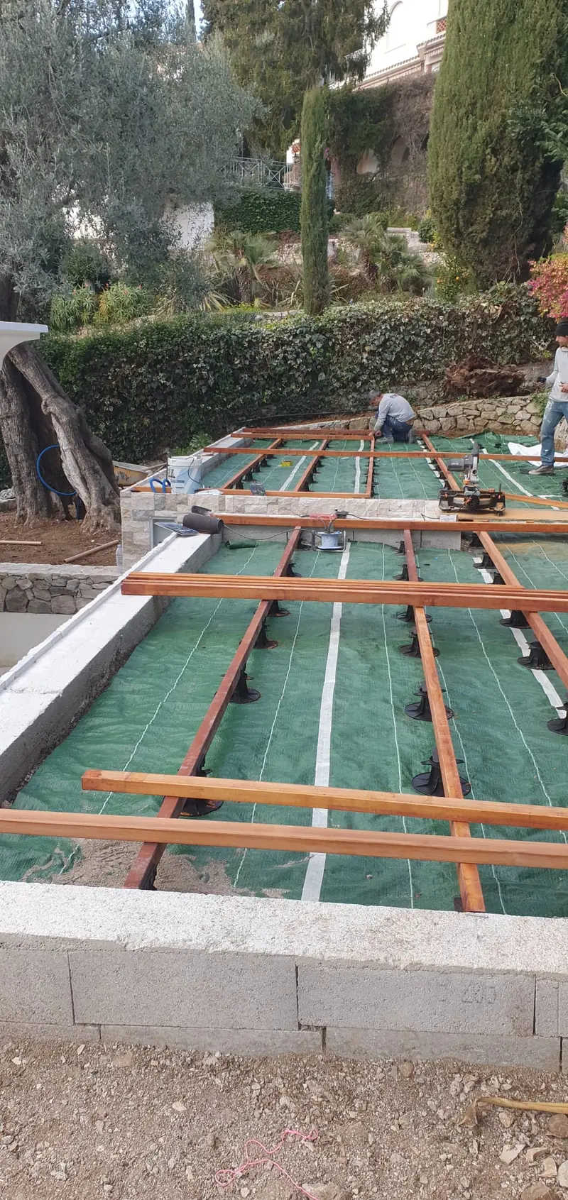 Plots et lambourdes d’une terrasse bois posée sur une plage de piscine