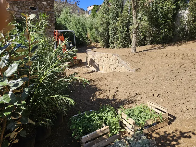 Terrassement à la mini-pelle le long d’un mur en pierre du pays
