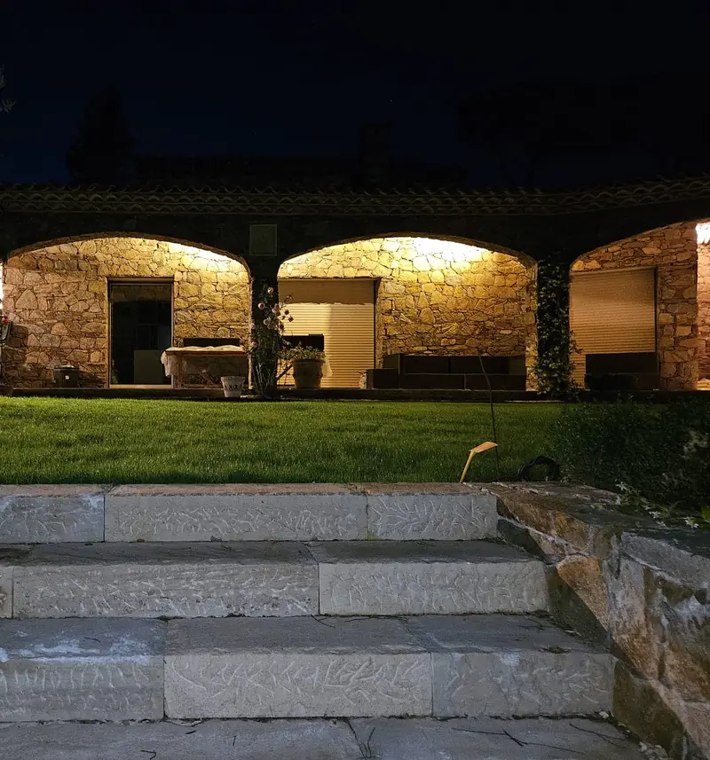 Façade à voûtes en pierre éclairée de nuit avec emmarchement en pierre